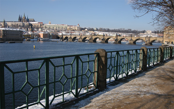 Vltava River embankment with Charles Bridge and Prague Castle in the winter with snow