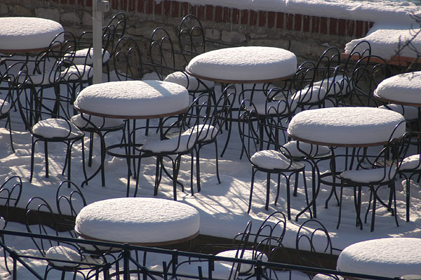 Unattended white tables in beer garden Lavka under Charles Bridge